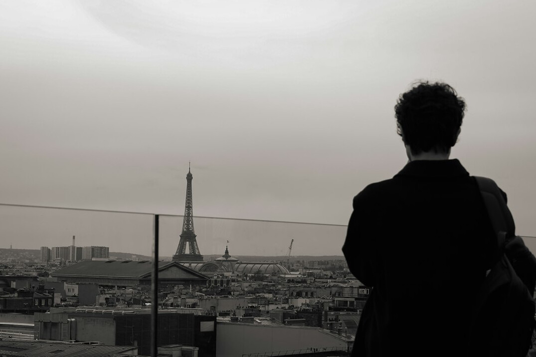 Business leader looking out of an office window over a European city skyline